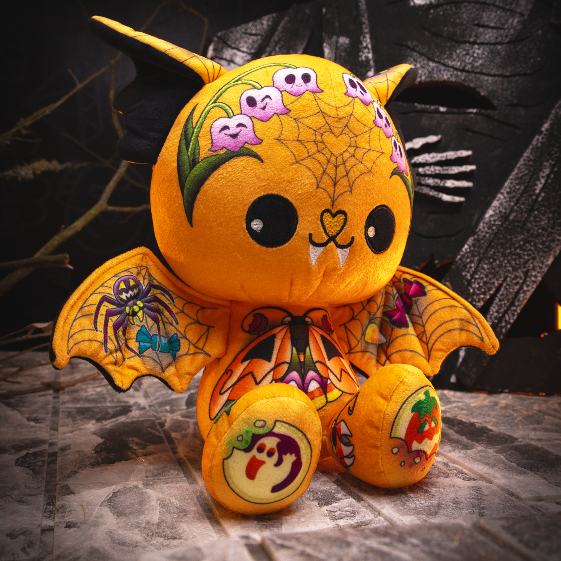 Halloween-themed plush toy with spider webs, bats, and ghosts on a dark background.