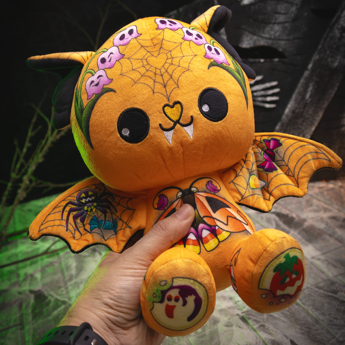 Halloween-themed plush toy held by a hand with a dark background
