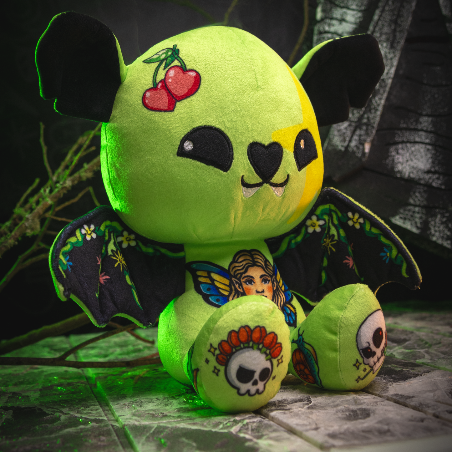 Green plush toy with tattoos and cherries on a dark background