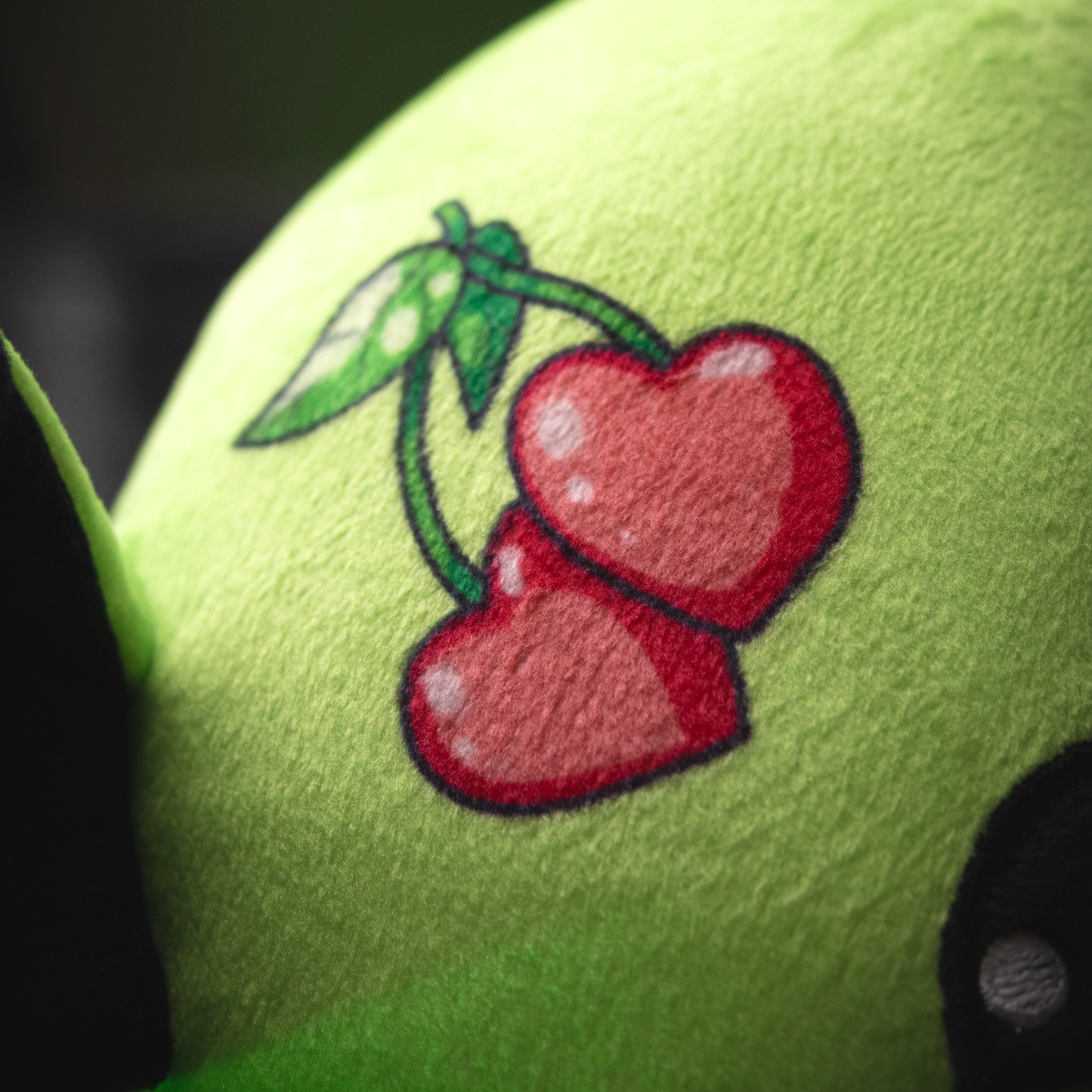 Embroidered cherries on a green fabric surface
